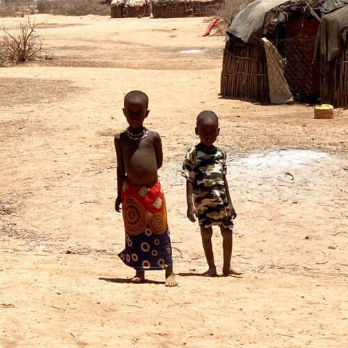Two children standing in front of a home in Kenya