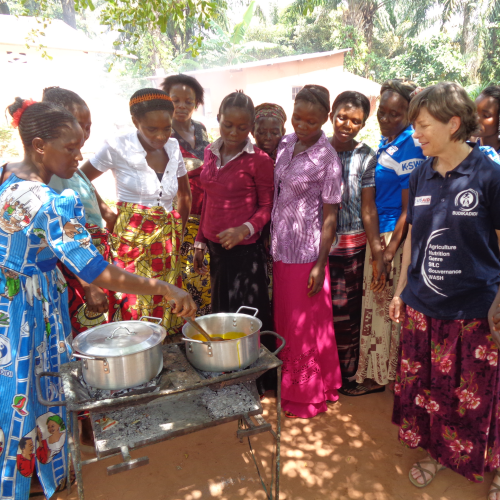 Group of women standing around cooking pots