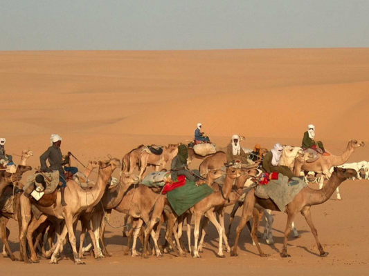 Pastoralists riding camels in the desert.